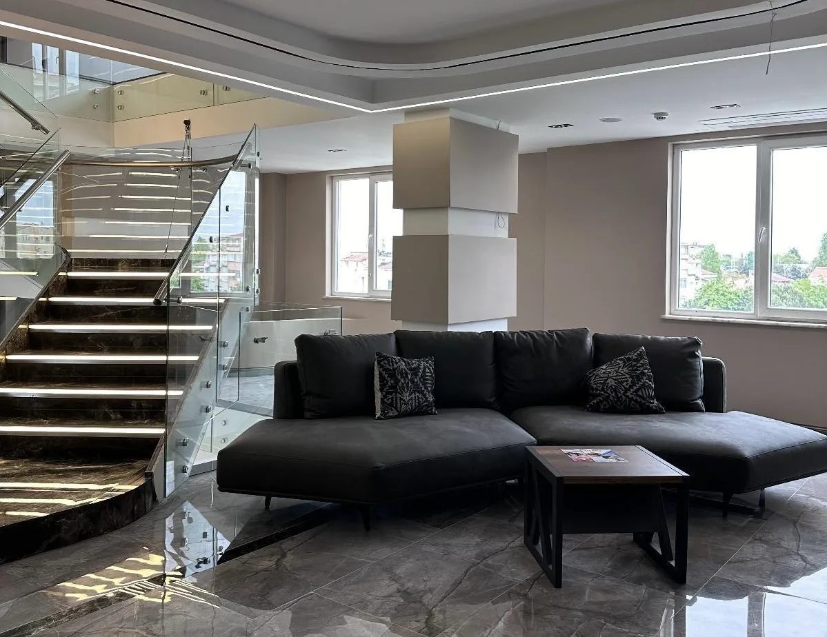 Patient lounge with modern sofas and a glass staircase at the Global Health Hair clinic in Istanbul